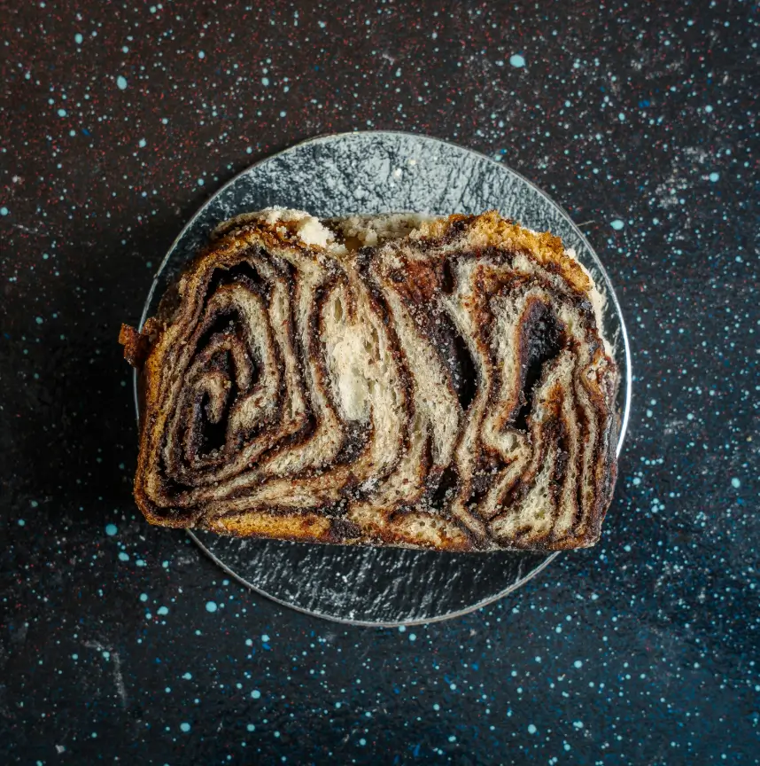 Overhead view of a thick slice of chocolate babka, showing rich swirls of dark chocolate in flaky, golden yeast dough