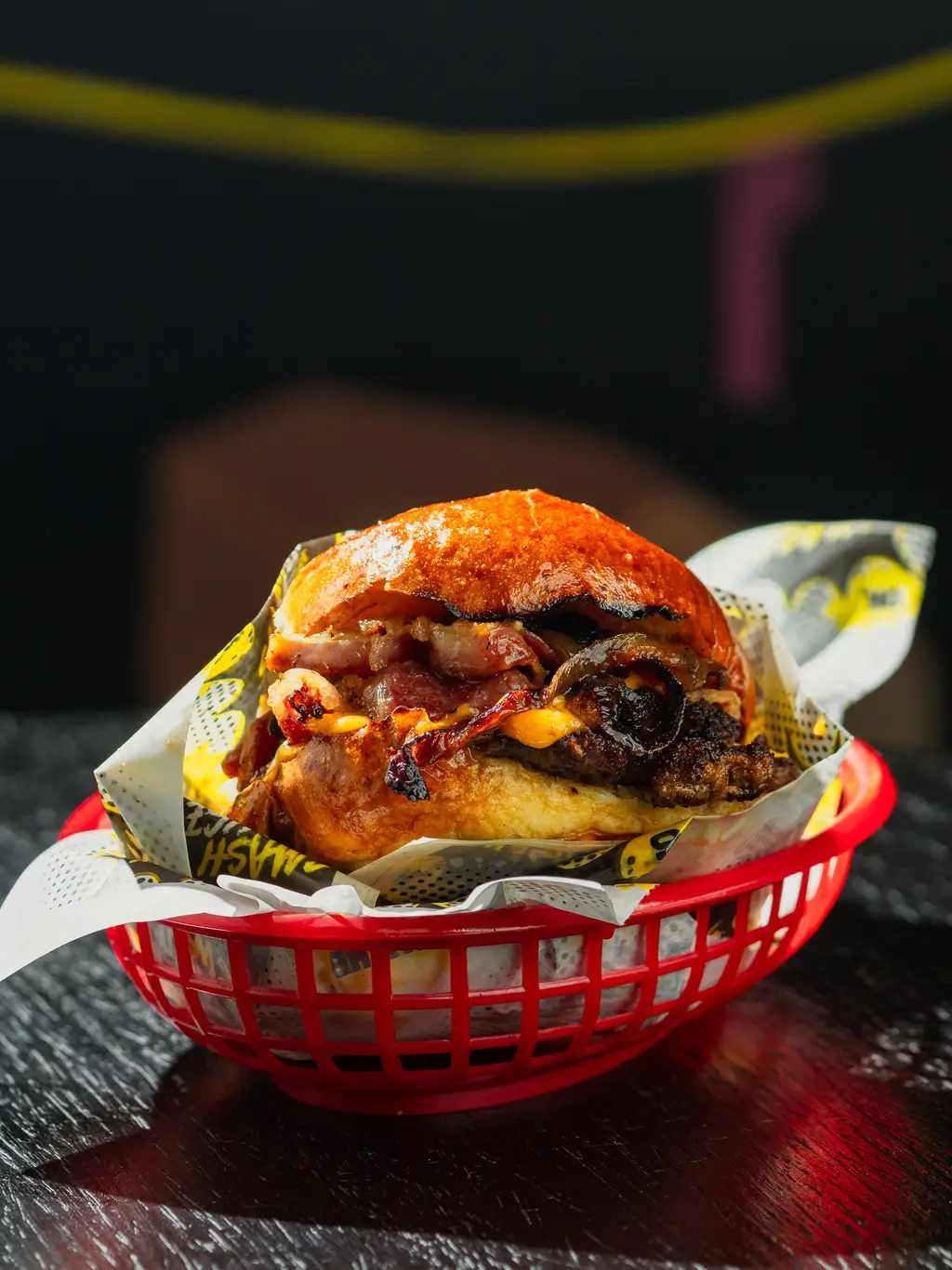 Beef bacon smash burger with crispy grilled onions, melted vegan cheese, and a glossy toasted bun in a red Smash House basket.