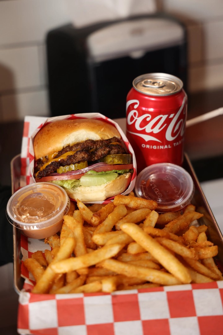 Burger tray with smash burger, fries, and dipping sauces.